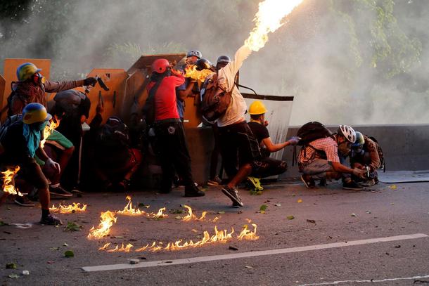 An opposition supporter throws a petrol bomb while clashing with riot security forces during a rally