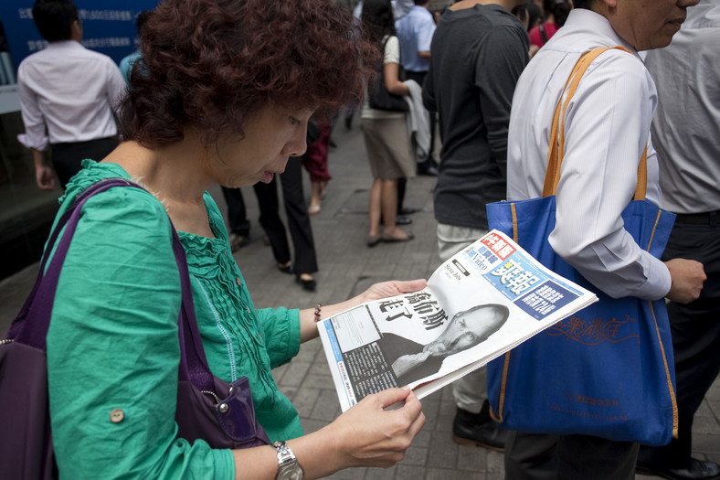 Kobieta w Hongkongu czyta bezpłatne wydanie gazety wydanej ze względu na śmierć Steve'a Jobsa, fot. Jerome Favre/Bloomberg