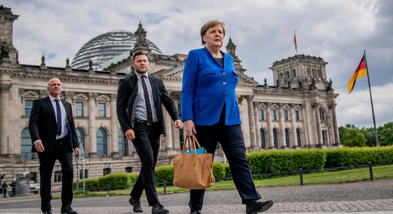 Chancellor Angela Merkel (CDU) walks to the Chancellery on foot, accompanied by her bodyguards, after the government questioning in the Bundestag in Berlin, Germany, Wednesday, May 13, 2020.  In the 159th session of the German Bundestag, besides the government questioning, discussions about foreign missions of the Bundeswehr are on the agenda. (Michael Kappeler/dpa via AP)