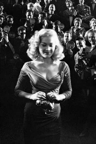 Aktorka Elaine Guy kokietuje tłum fotografów na Festiwalu filmowym w Cannes. Rok 1957