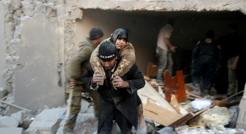 A man carries a woman from the rubble of a building following reported airstrikes on Aleppo's rebel-held district of al-Hamra on November 20, 2016