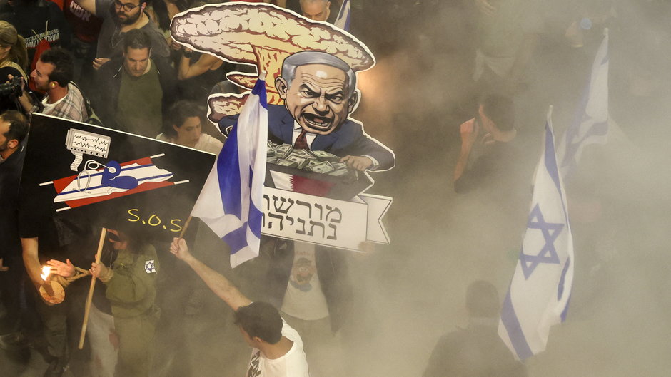 Krewni i zwolennicy izraelskich zakładników przetrzymywanych w Strefie Gazy od czasu ataków bojowników Hamasu z 7 października ub.r. trzymają transparenty, machają izraelskimi flagami i trzymają karykaturę premiera Izraela Benjamina Netanjahu podczas demonstracji przed resortem obrony w Tel Awiwie, 6 kwietnia 2024 r.