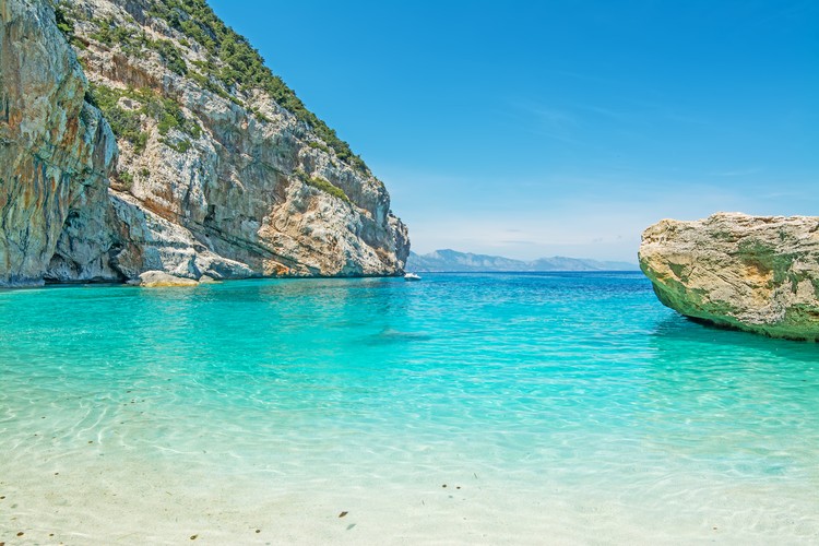 <strong>Zatoka Orosei – miejsce dla odkrywców</strong>
<br></br>
Miejsce, w którym morze spotyka się z górami, tworząc wyjątkowy krajobraz, z przepięknymi piaszczystymi plażami, ukrytymi przed światem. Ta część Sardynii w dużej mierze dostępna jest tylko łodzią, ale uchodzi też za najbardziej spektakularną. 
Zatoka Orosei rozciąga się na długości 70 kilometrów, układając się w łagodny kształt półksiężyca wzdłuż wschodniego brzegu wyspy, rozciągając się pomiędzy Punta Nera na północy aż po Capo Monte Santu na południu. Doskonałym punktem stanowiącym bazę wypadową do zwiedzania zarówno okolicy jak i całego wschodniego wybrzeża jest miasteczko Cala Gonone. Łatwo można dotrzeć stamtąd zarówno na jedną z przepięknych plaż, jak i w najwyższe góry Sardynii – Gennargentu – idealne miejsce dla miłośników trekkingu.
<br></br>
40-kilometrowy odcinek na południe od Cala Gonone jest pozbawiony cywilizacji i charakteryzuje się pionowymi wapiennymi klifami pośród których ukryte są plaże i głębokie groty. Prawdopodobnie najpiękniejsza plaża w tej zatoce to Cala Mariolu podzielona na dwie części przez wypiętrzające się z piasku skały. Wypolerowane przez wodę wapienie w niczym jednak nie utrudniają kąpieli w szafirowym morzu. Sceneria idealna na wymarzone wakacje. 
<br></br>
Źródło: r.pl/wlochy/sardynia