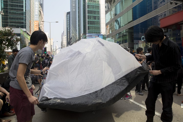 Protesty w Hongkongu mają także podłoże klasowe. Po jednej stronie ekonomicznego sporu znajduje się zamożna grupa mandaryńskojęzyczna, przybywająca z kontynentalnych Chin, po drugiej natomiast rosnąca ubożejąca lokalna grupa społeczna mówiąca po kantońsku. <br> Na zdj. demonstranci ustawiają namiot na ulicy Nathan Road w dzielnicy Mong Kok. 17.10.2014