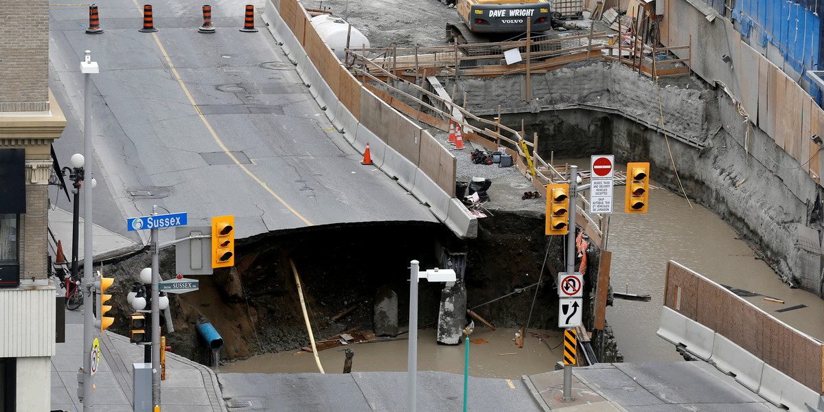 Workers look at a large sinkhole in Ottawa, Ontario, Canada.