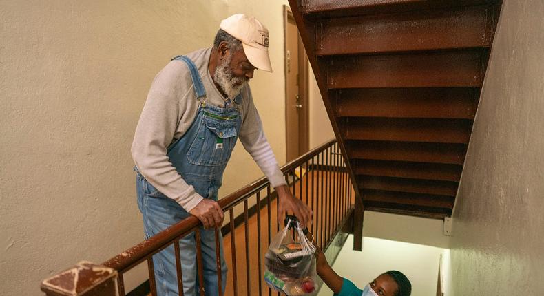 A Citymeals on Wheels worker delivers a bag of groceries to an older man inside an apartment building in New York City.Citymeals on Wheels