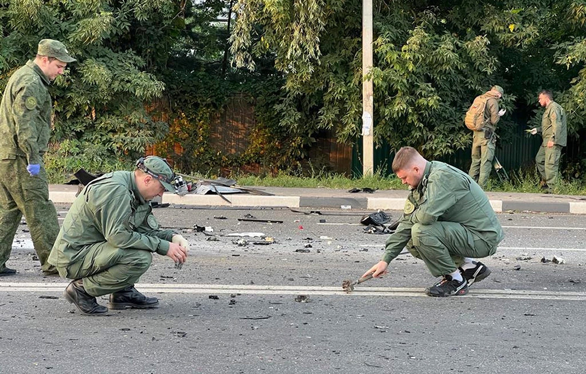Na videosnímke vyšetrovatelia na mieste výbuchu auta novinárky a politologičky Darii Duginovej 21. augusta 2022 v Moskve.