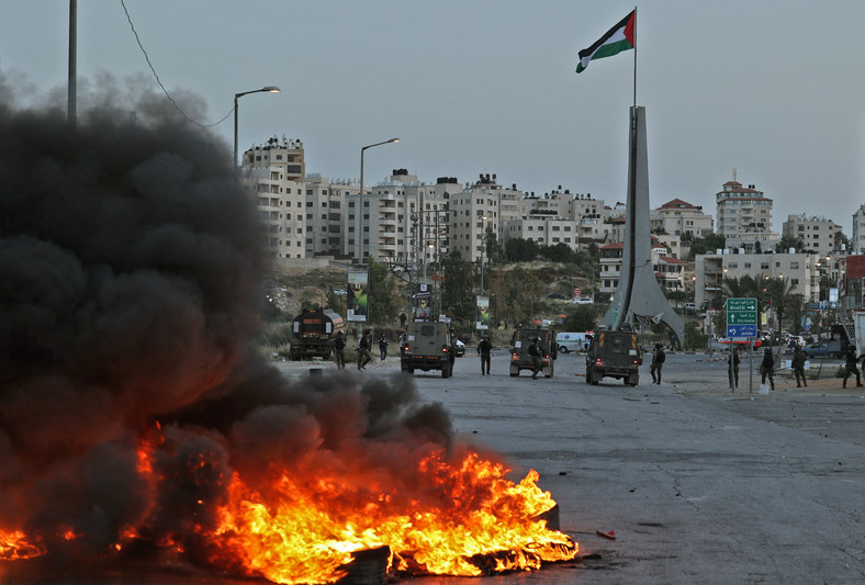 Napięcie między Izraelem a Palestyńczykami na Zachodnim Brzegu Jordanu narasta od wielu miesięcy. Tutaj zdjęcie z 22 maja 2022 r. Izraelscy strażnicy graniczni i ich pojazdy zajmują pozycję w pobliżu osiedla Beit El przy północnym wjeździe do miasta Ramallah na okupowanym Zachodnim Brzegu w wyniku starć z palestyńskimi protestującymi po demonstracji potępiającej coroczną "Paradę Flagi" przez Jerozolimę. Co roku marsz wzbudza gniew strony palestyńskiej