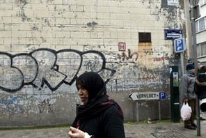 A woman passes close to the house where Salah Abdeslam was arrested after a shootout with police in 