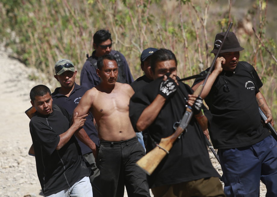 Members of the Community Police of the FUSDEG (United Front for the Security and Development of the State of Guerrero) walk with a man they captured after a shootout against a group that villagers suspect are members of a local gang, at a hill in the village of Petaquillas, on the outskirts of Chilpancingo, Guerrero, February 1, 2015.