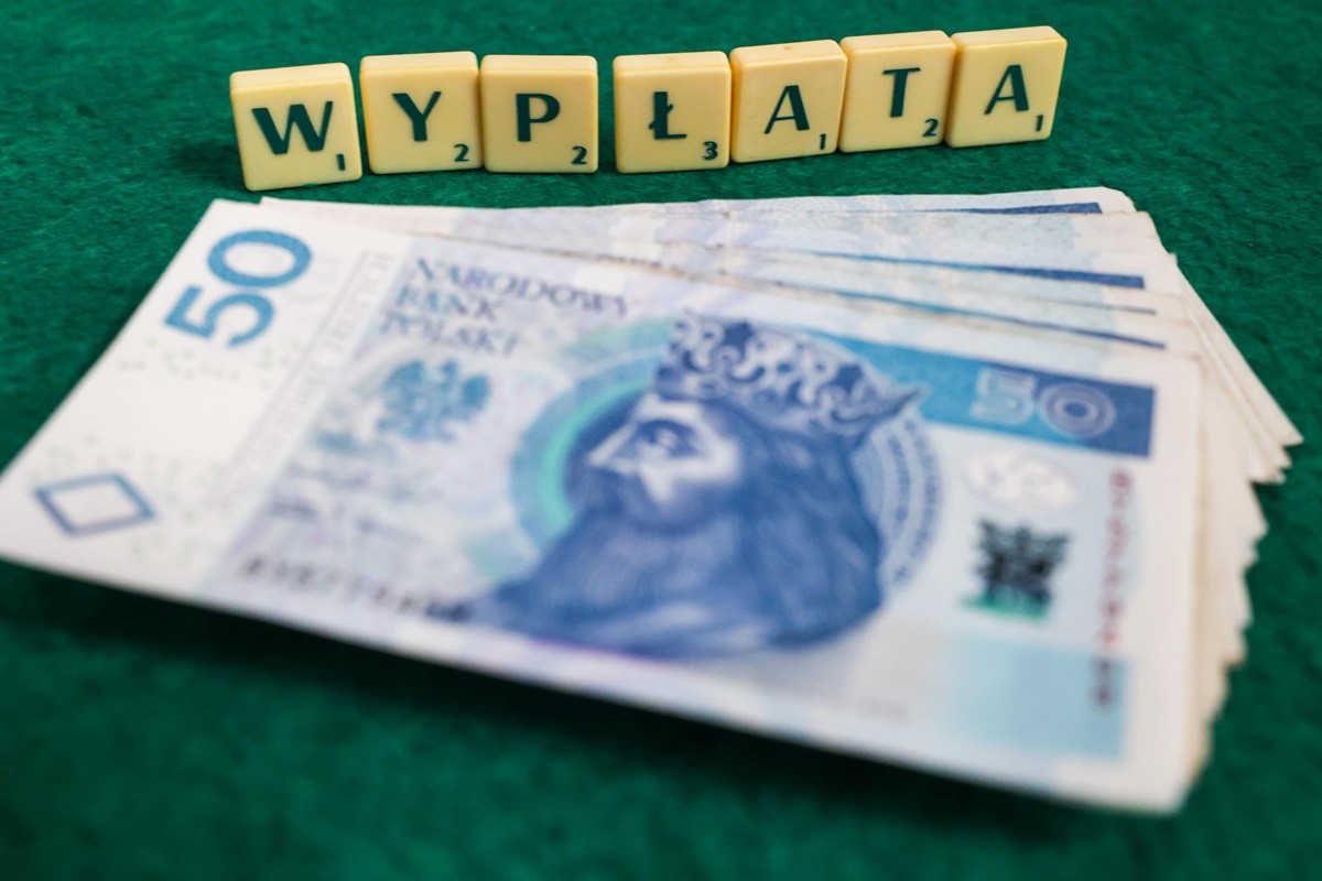 Polskie banknoty leżą na stole, w tle napis "wypłata" - Nowa płaca minimalna od 1 stycznia 2026 r.