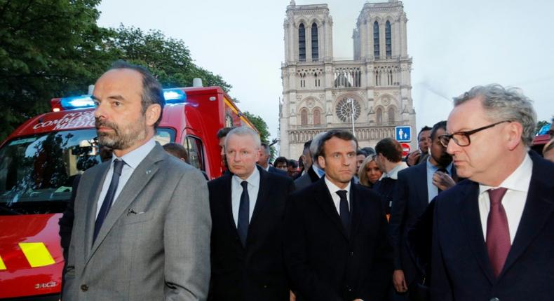 French Prime Minister Edouard Philippe (L), and French President Emmanuel Macron (3rd L) gather near the entrance of the Notre-Dame Cathedral in Paris, as flames engulf its roof