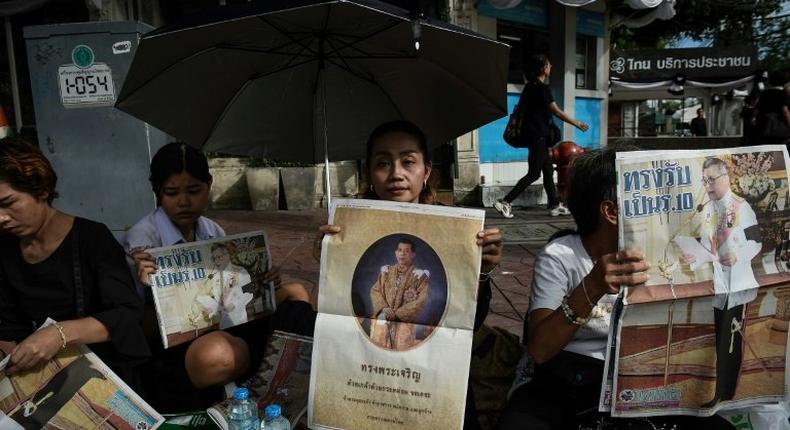 People hold newspaper images of Thailand's new King Maha Vajiralongkorn outside the Grand Palace in Bangkok