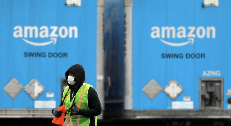 FILE PHOTO: A worker in a face mask walks by trucks parked at an Amazon facility as the global coronavirus outbreak continued in Bethpage on Long Island in New York, U.S., March 17, 2020. REUTERS/Andrew Kelly/File Photo