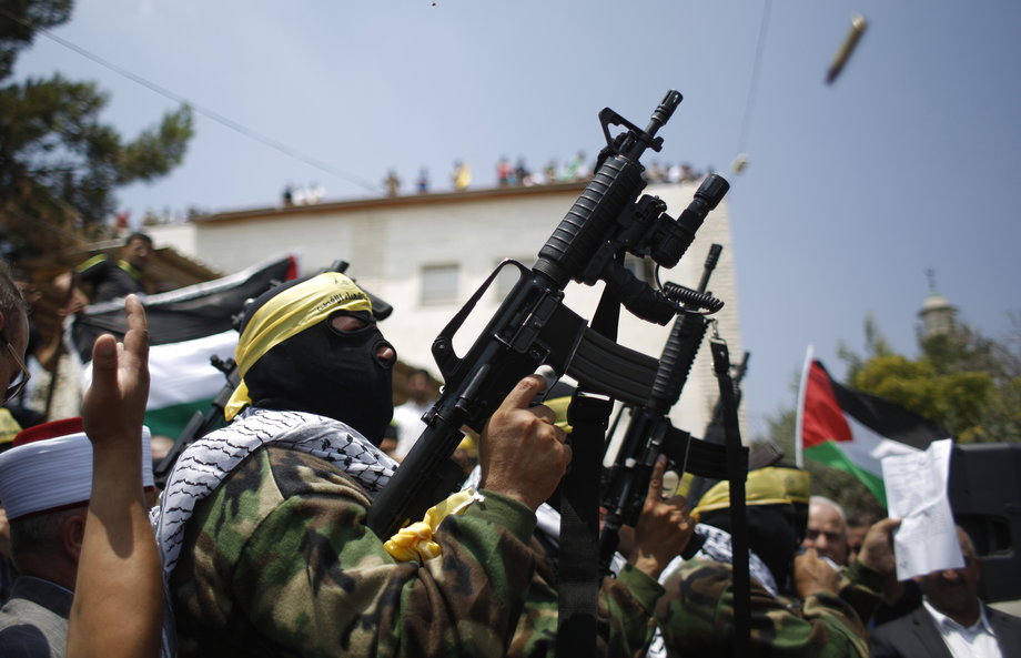 A Palestinian gunman fires in the air during the funeral of Mahmoud al-Shawamrah in the West Bank town of Al-Ram near Jerusalem July 22, 2014.