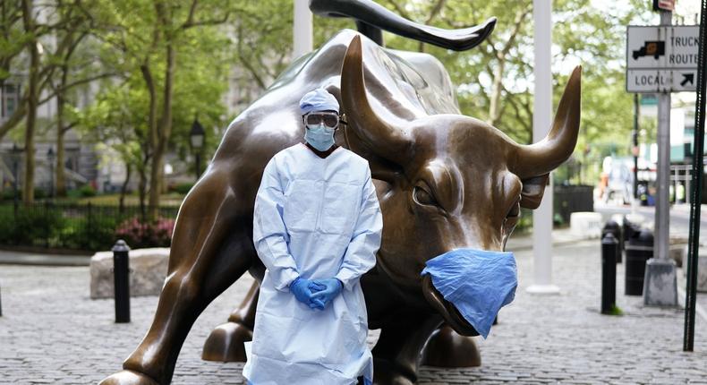Julius Shakari, a California man, wears PPE in front of Wall Street's Charging Bull.
