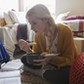 Female college student eating and studying on floor in dorm room