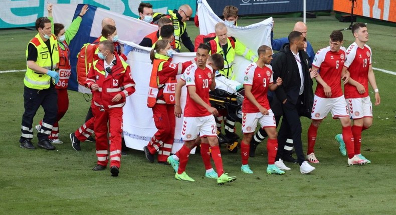 Denmark's players gather as medics treat midfielder Christian Eriksen during the Euro 2020 match against Finland Creator: WOLFGANG RATTAY