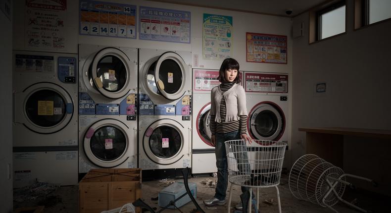 A woman poses inside a laundromat destroyed by the Fukushima Daiichi nuclear disaster.