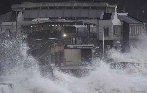 Passengers board a train during heavy seas and high winds in Dawlish in south west Britain