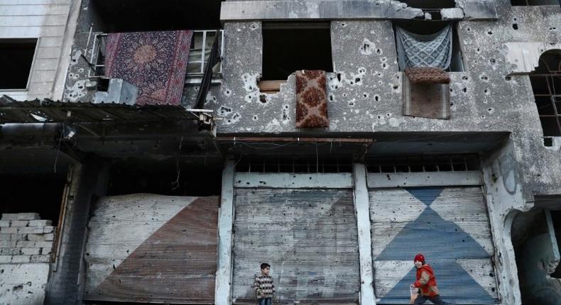 Syrian children play next to a ruined buidling in the rebel-held town of Douma on the eastern outskirts of Damascus on January 9, 2017