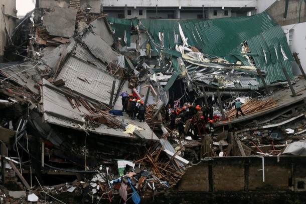 Military officials and fire brigade members work during a rescue mission after a building collapsed 