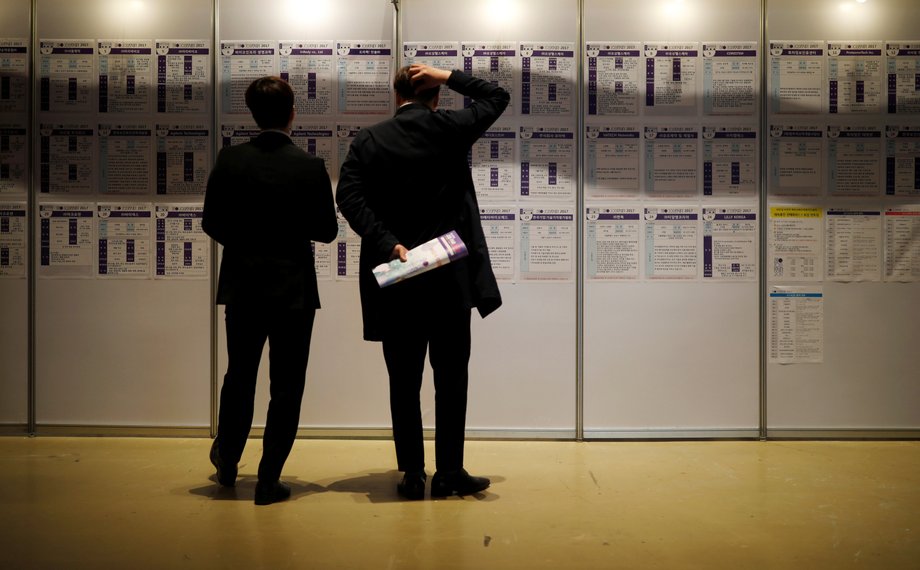 Men look at recruiting information during a job fair in Seoul, South Korea, April 12, 2017.