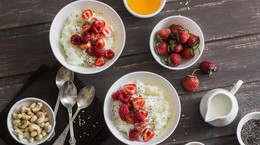 Coconut milk sweet rice porridge with berries on a wooden background, top view. Healthy gluten free vegetarian breakfast or dessert