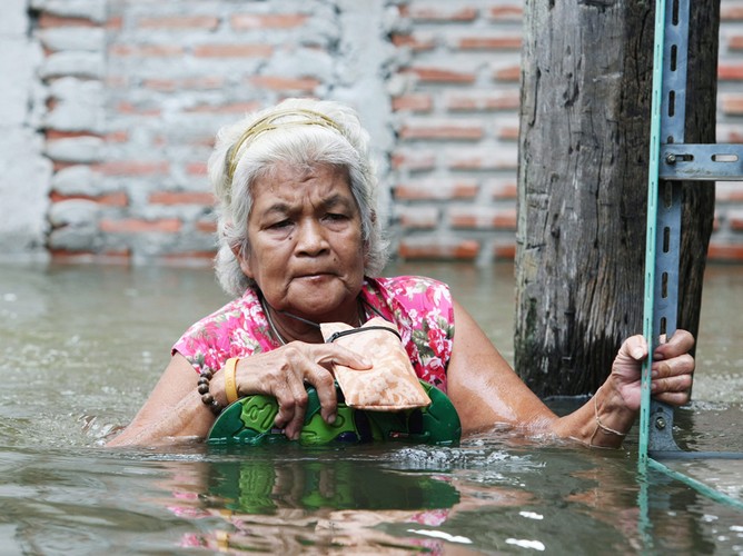 Starsza kobieta przedzierająca się przez zalane ulice Pak Kret w prowincji Nonthaburi na obrzeżach Bangkoku. 16 października 2011 Tajlandia