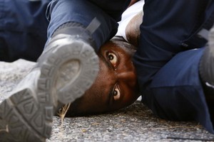 A man protesting the shooting death of Alton Sterling is detained by law enforcement near the headqu