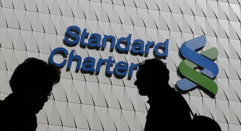 Passersby walk in front of the main branch of Standard Chartered in Hong Kong, in this January 8, 2015 file photo. REUTERS/Bobby Yip