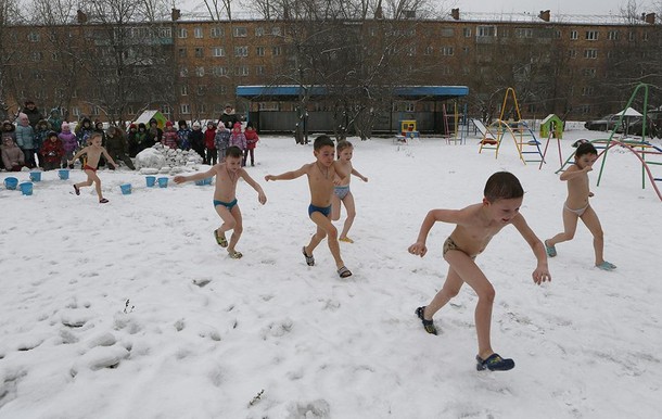 Children watch their classmates pour cold water on themselves, under the watch of fitness coach Oksa