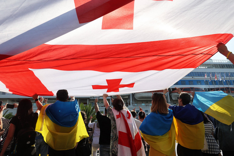 Demonstranci trzymają flagę Gruzji podczas akcji protestacyjnej przeciwko przybyciu statku wycieczkowego Astoria Grande z około 800, głównie rosyjskimi pasażerami na pokładzie. Batumi, 31 lipca 2023 r