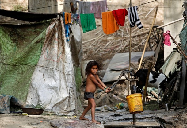 A child uses a hand pump to extract water on the banks of the river Yamuna in New Delhi