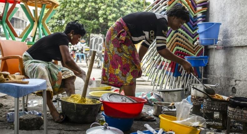 Women prepare food at a street restaurant in Kinshasa, on December 21, 2016