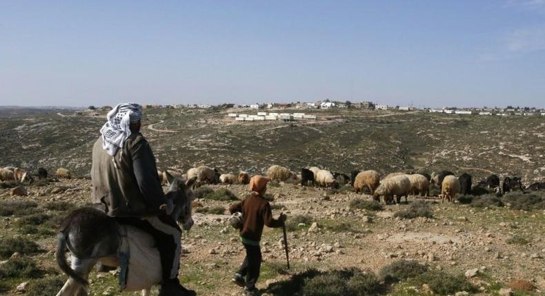 A Palestinian man and a child are seen in the village of Sair near the Israeli settlement of Metzad