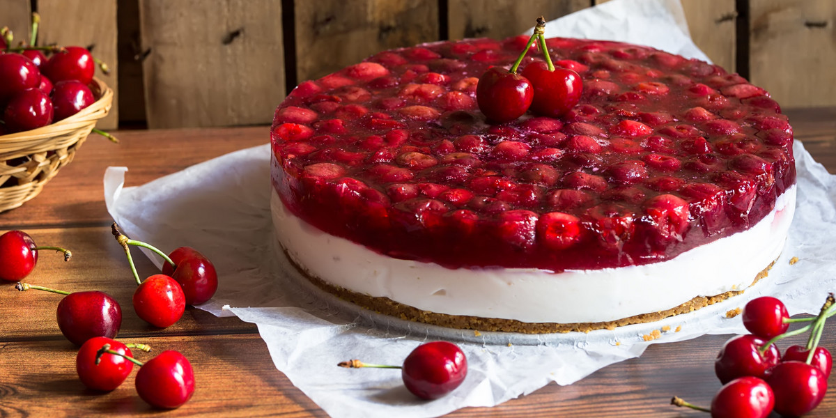 Cold cheesecake with cherry jelly on wooden background, tasty summer dessert