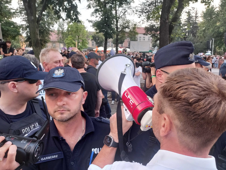 Sławomir Nitras z megafonem otoczony kordonem policji