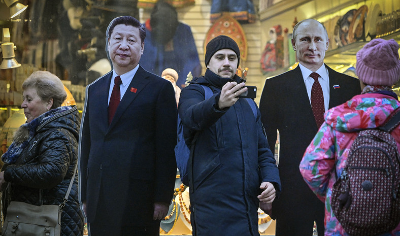 Ludzie przechodzą obok kartonowych obrazów przedstawiających przywódcę Chin Xi Jinpinga (po lewej) i prezydenta Rosji Władimira Putina na turystycznej ulicy Arbat w centrum Moskwy, 15 listopada 2023 r.