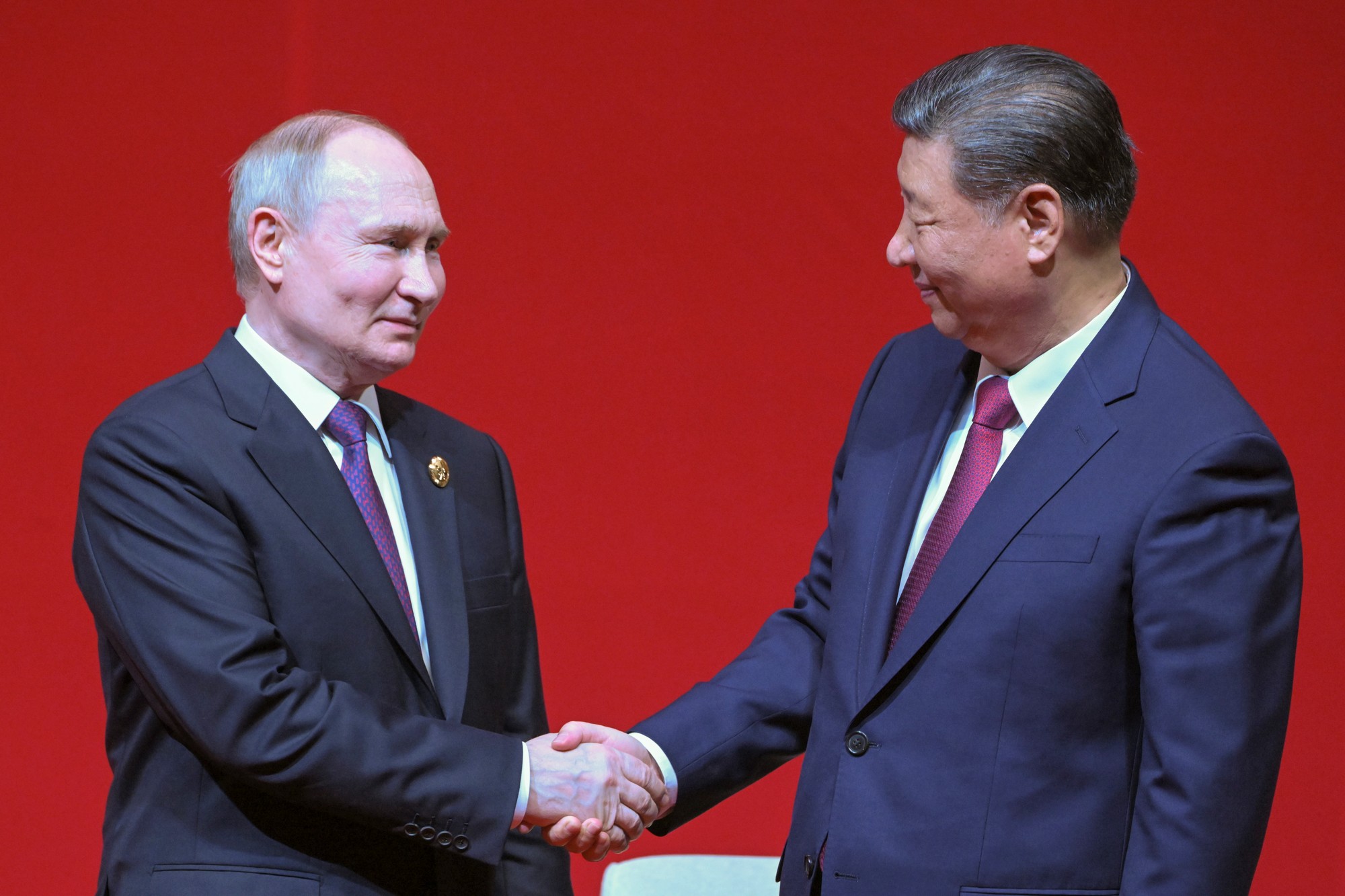 Ruský prezident Vladimir Putin (vľavo) a čínsky prezident Si Ťin-pching si podávajú ruky počas koncertu pri príležitosti 75. výročia nadviazania diplomatických vzťahov.
