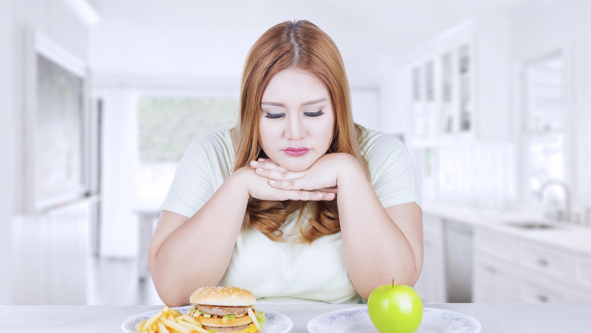 Confused woman choose apple or hamburger