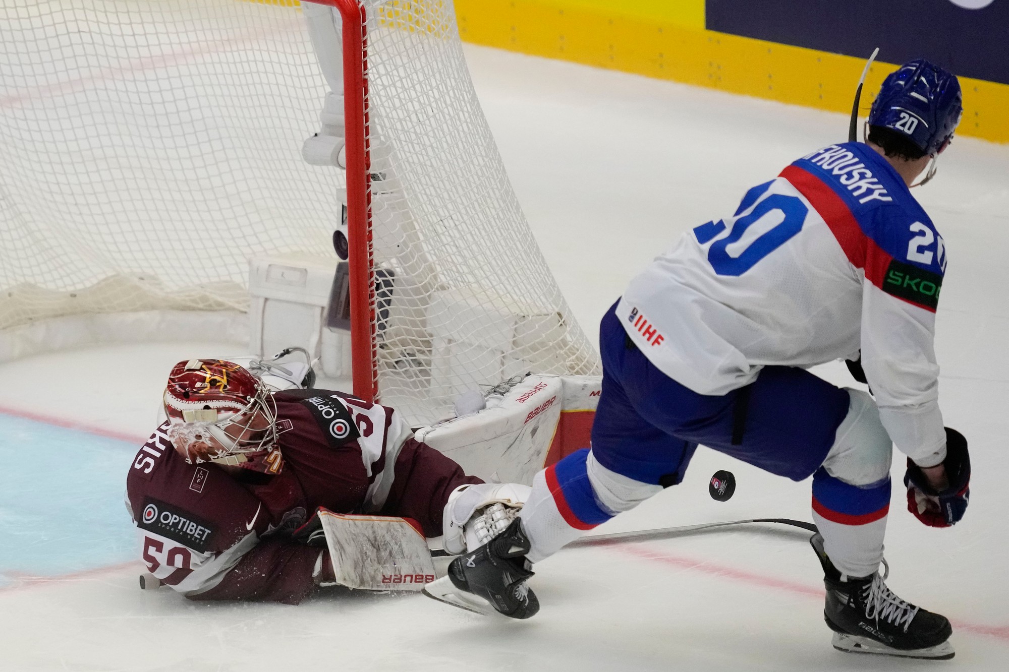 Lotyšský brankár Kristers Gudlevskis (vľavo) bráni pred Slovákom Jurajom Slafkovským v samostatných nájazdoch.