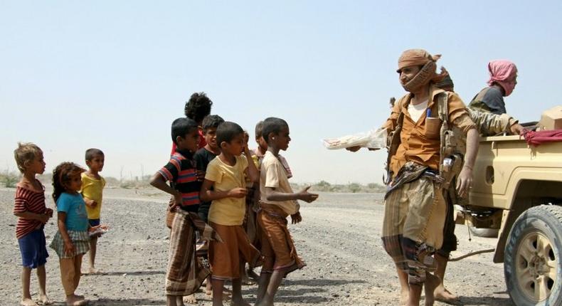 Pro-regime fighters give food to Yemeni children on the road leading to the southwestern port city of Mokha, on January 26, 2017