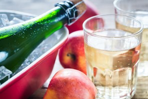 Bottle and two glasses of cider on the wooden background