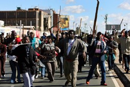 Striking public servants run through the streets outside the Chris Hani Baragwanath Hospital in Soweto near Johannesburg, South Africa