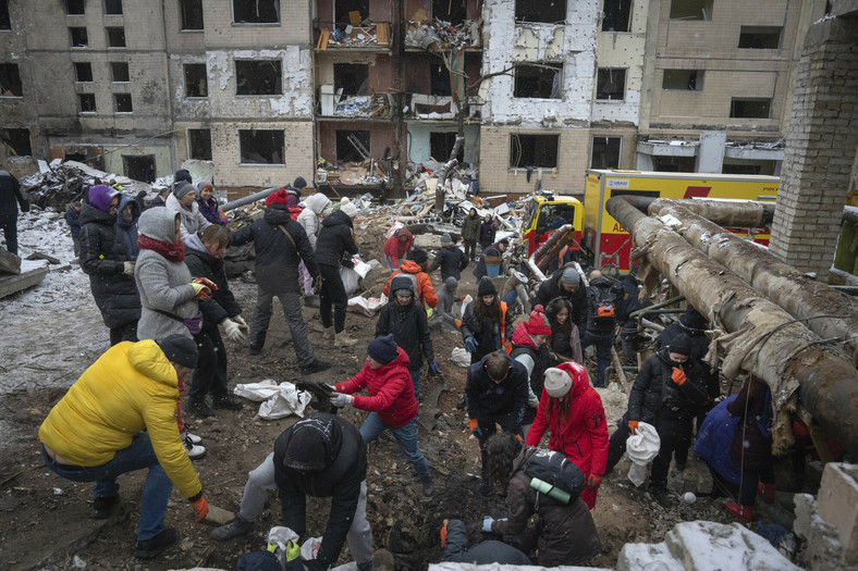 Wolontariusze i mieszkańcy usuwają gruzy budynku mieszkalnego zniszczonego po rosyjskim ataku na Kijów, 3 stycznia 2024 r.