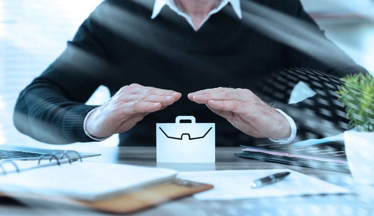 Mężczyzna osłania dłońmi wirtualną teczkę na dokumenty.