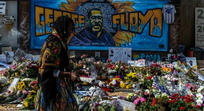 A woman burns sage and offers prayers as she pays her respects at a makeshift memorial in honor of George Floyd, who died while in police custody on May 25