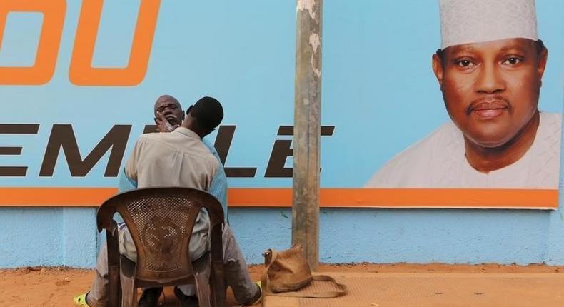 A man gets a haircut and a shave in front of a campaign poster of incarcerated opposition candidate Hama Amadou in Niamey, Niger, February 15, 2016. Niger holds presidential and legislative elections on Sunday. 