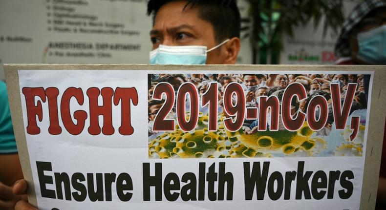 A health worker wearing a face mask holds a placard during a protest in front of a government hospital in Manila